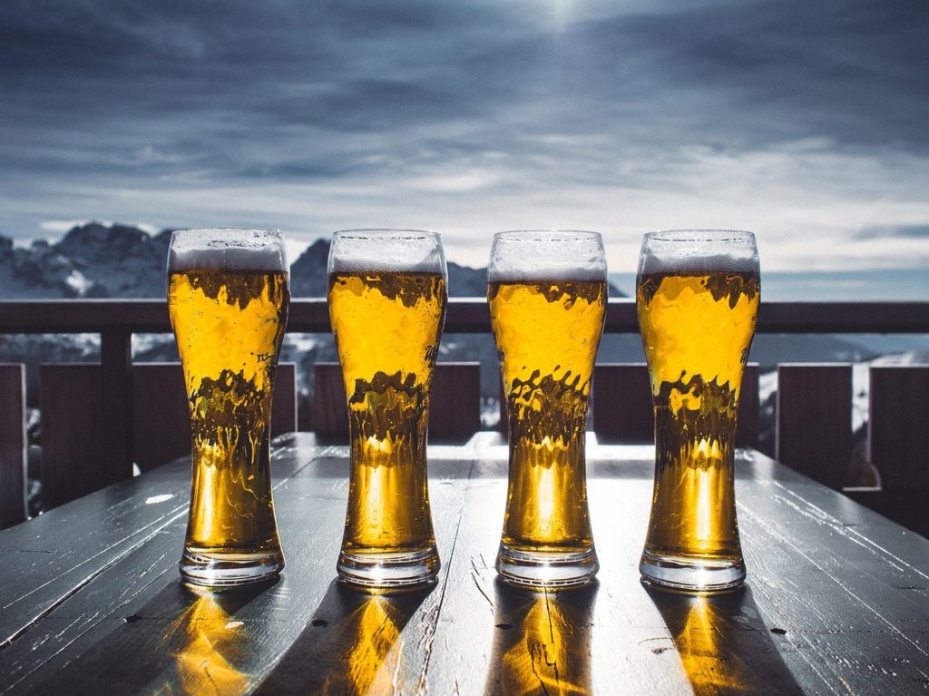 Glasses of beer on table overlooking lake